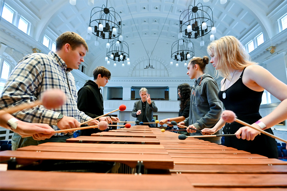 Group of students playing mirimba, with a teacher conducting them at the end of the marimba.